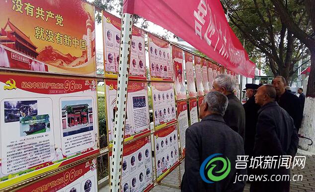 过往行人驻足观看图片展。